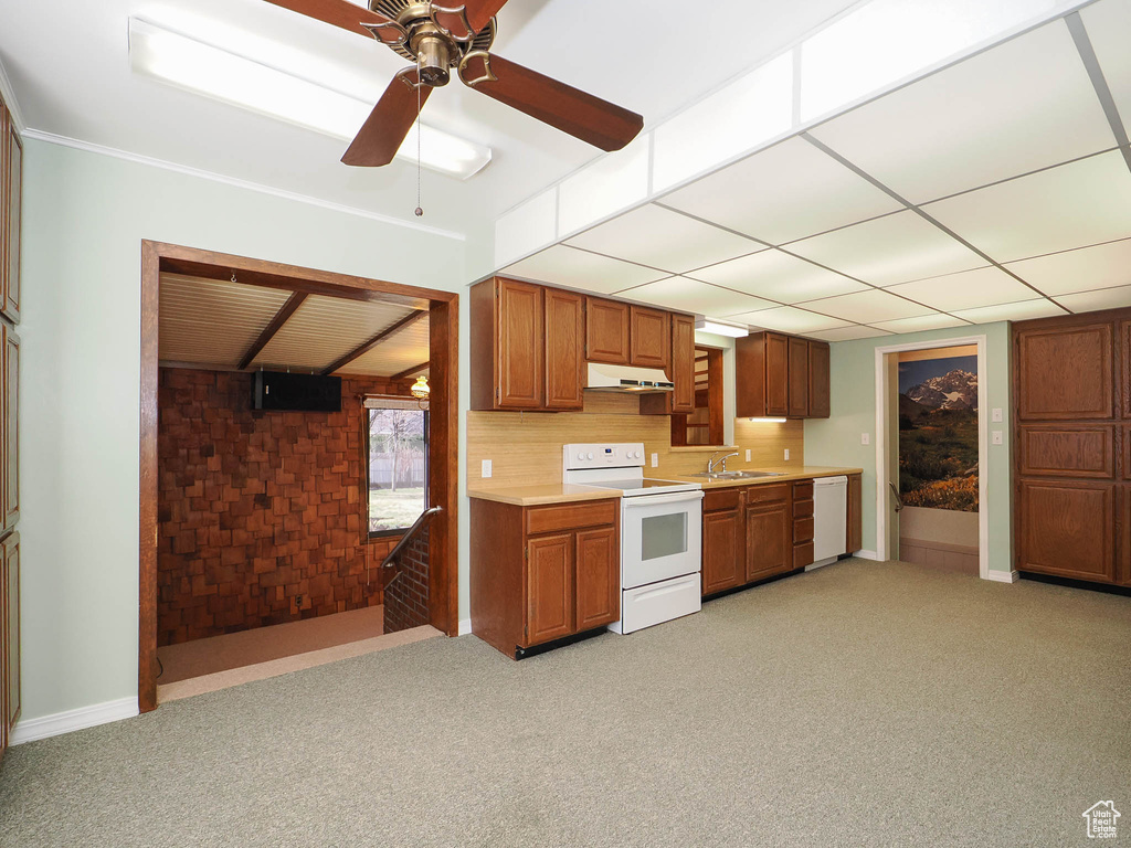Kitchen featuring light carpet, white appliances, sink, and ceiling fan