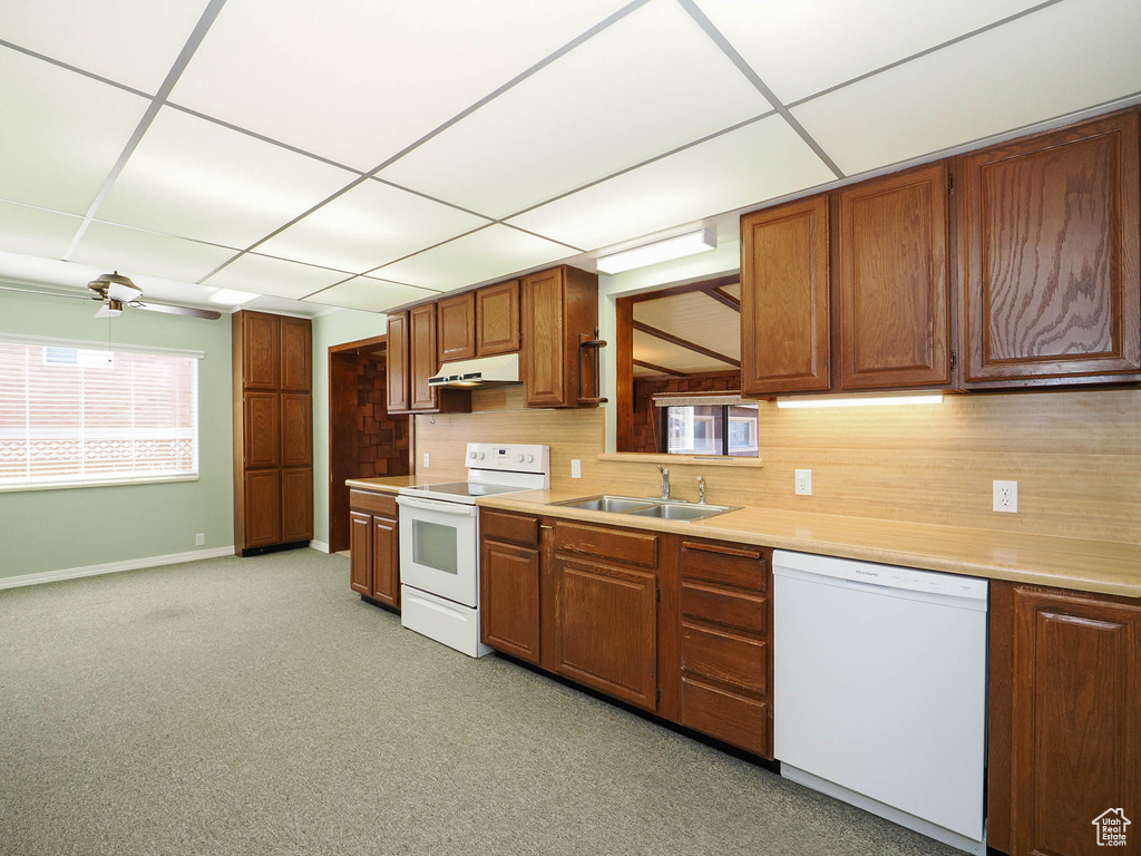 Kitchen with white appliances, ceiling fan, sink, light carpet, and a drop ceiling