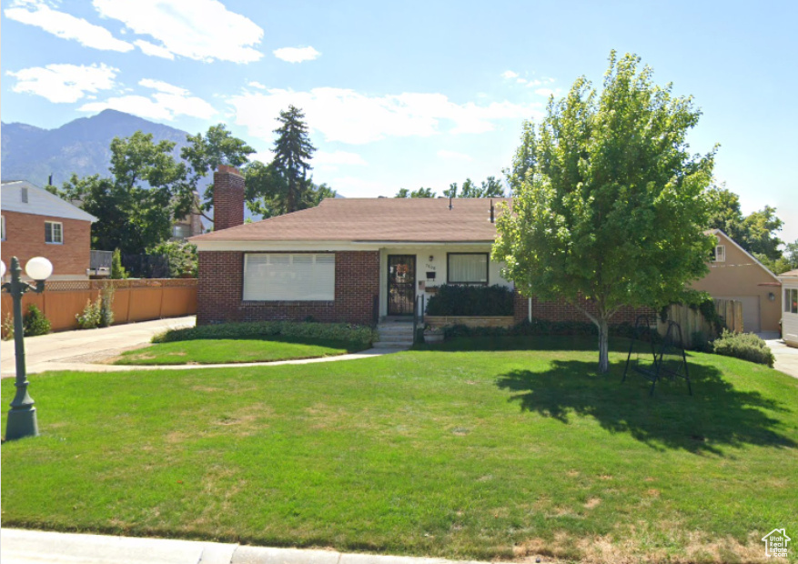 View of front of home with a front yard and a mountain view