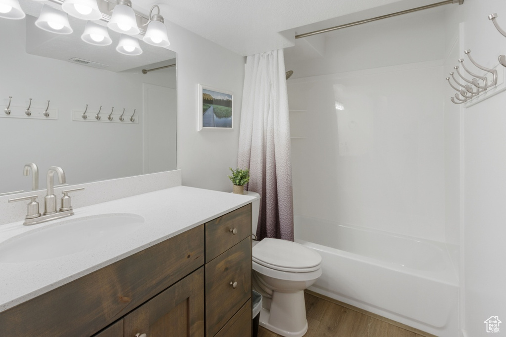 Full bathroom featuring hardwood / wood-style floors, toilet, vanity, and shower / tub combo with curtain
