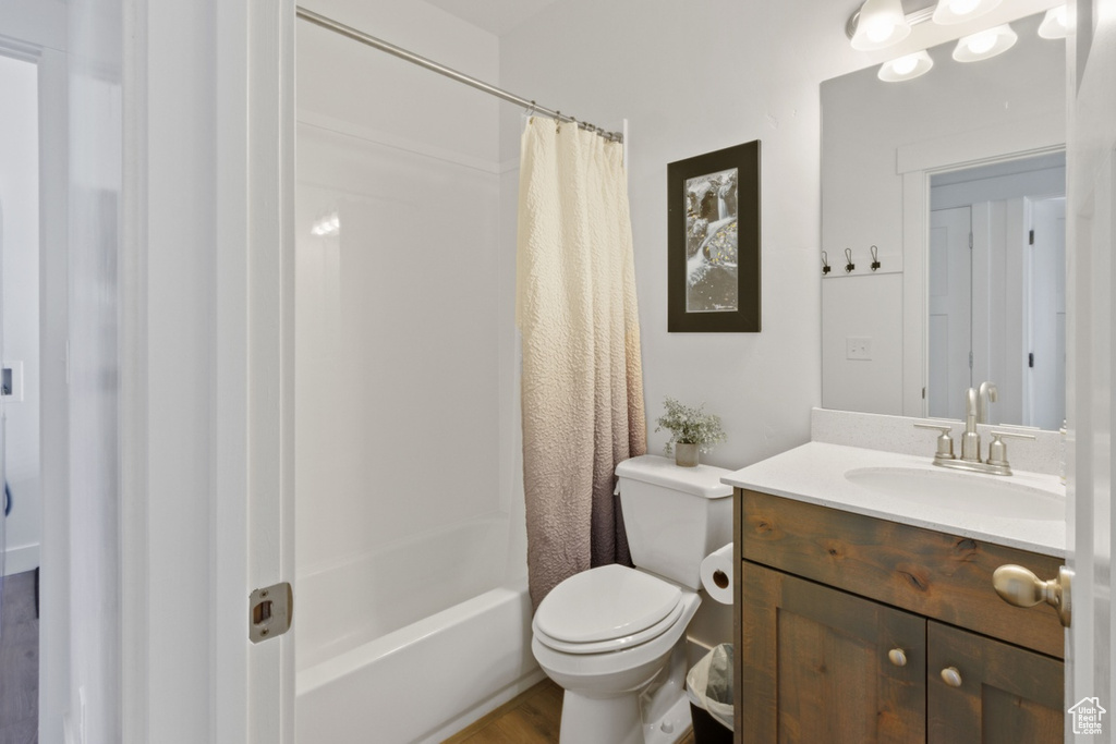 Full bathroom featuring shower / bath combo, hardwood / wood-style flooring, toilet, and vanity