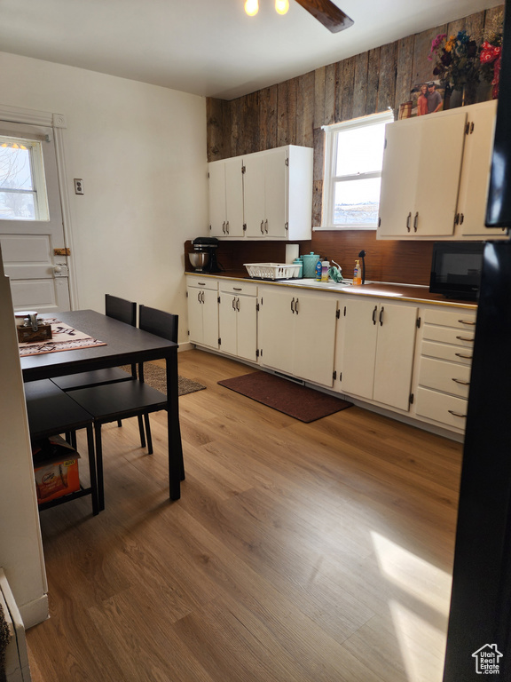 Kitchen with backsplash, white cabinets, ceiling fan, hardwood / wood-style floors, and sink