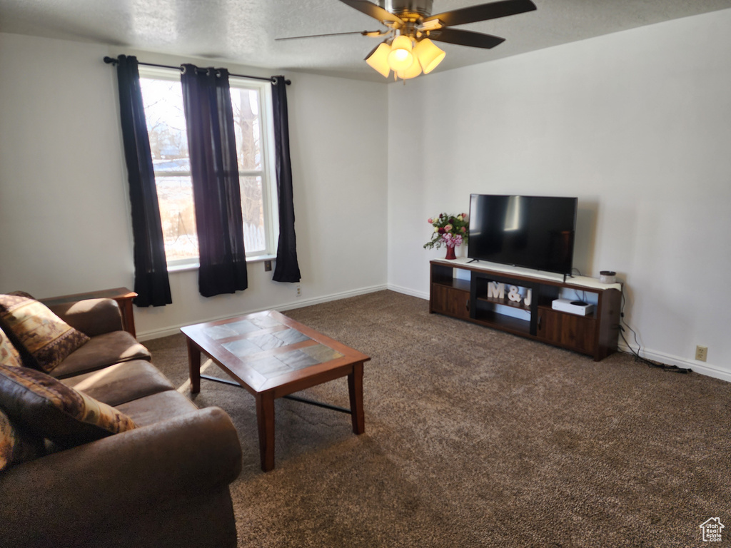 Living room with dark colored carpet, a textured ceiling, and ceiling fan