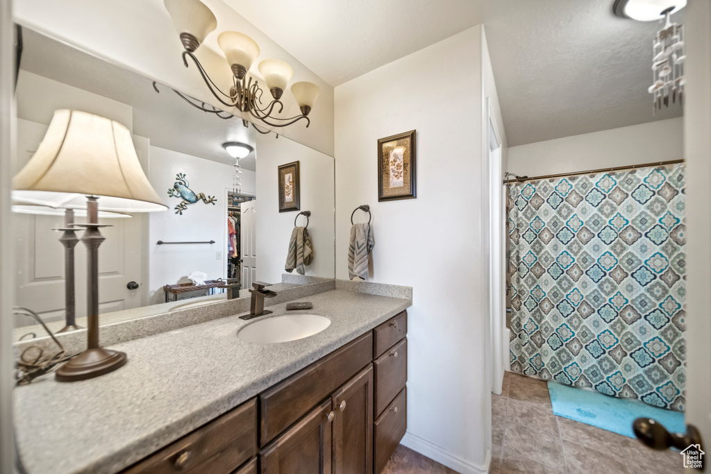 Bathroom with vanity, a notable chandelier, and tile floors