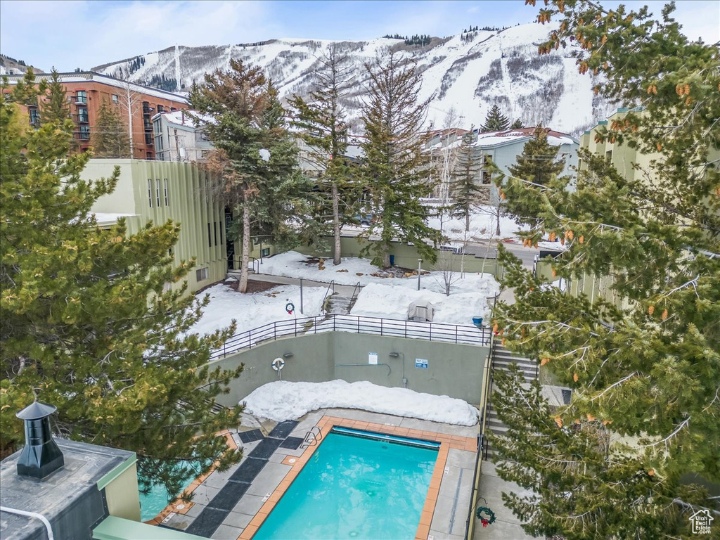 Snow covered pool with a patio and a mountain view