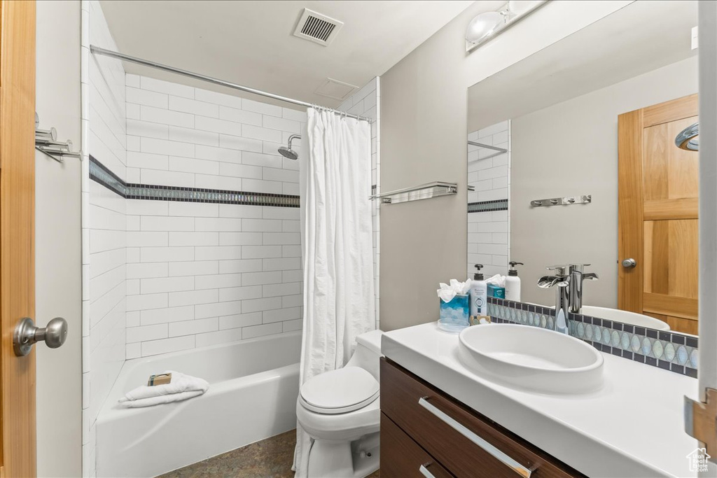 Full bathroom with vanity, shower / bath combo, and toilet