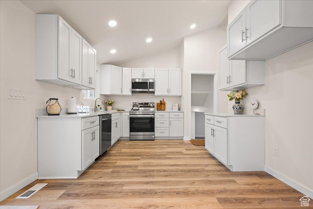Kitchen featuring white cabinets, stainless steel appliances, and light hardwood / wood-style floors