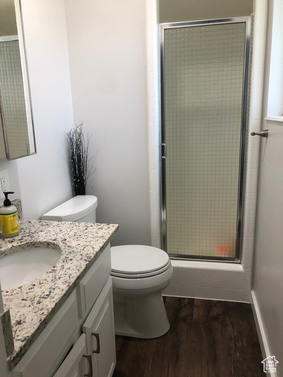 Bathroom featuring an enclosed shower, vanity with extensive cabinet space, hardwood / wood-style flooring, and toilet