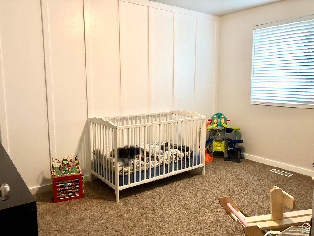 Carpeted bedroom featuring a crib