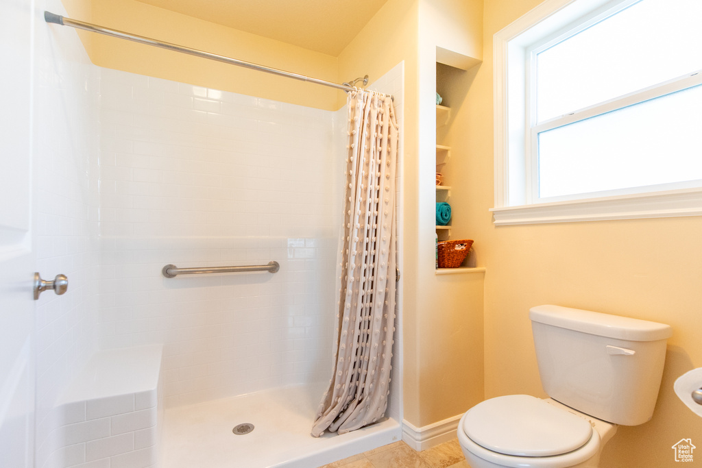 Bathroom featuring a wealth of natural light, toilet, and a shower with shower curtain