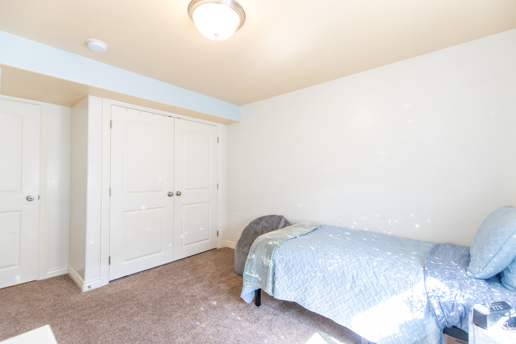 Bedroom with light carpet and a closet