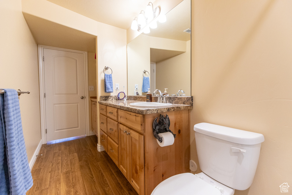 Bathroom with vanity, toilet, a chandelier, and wood-type flooring