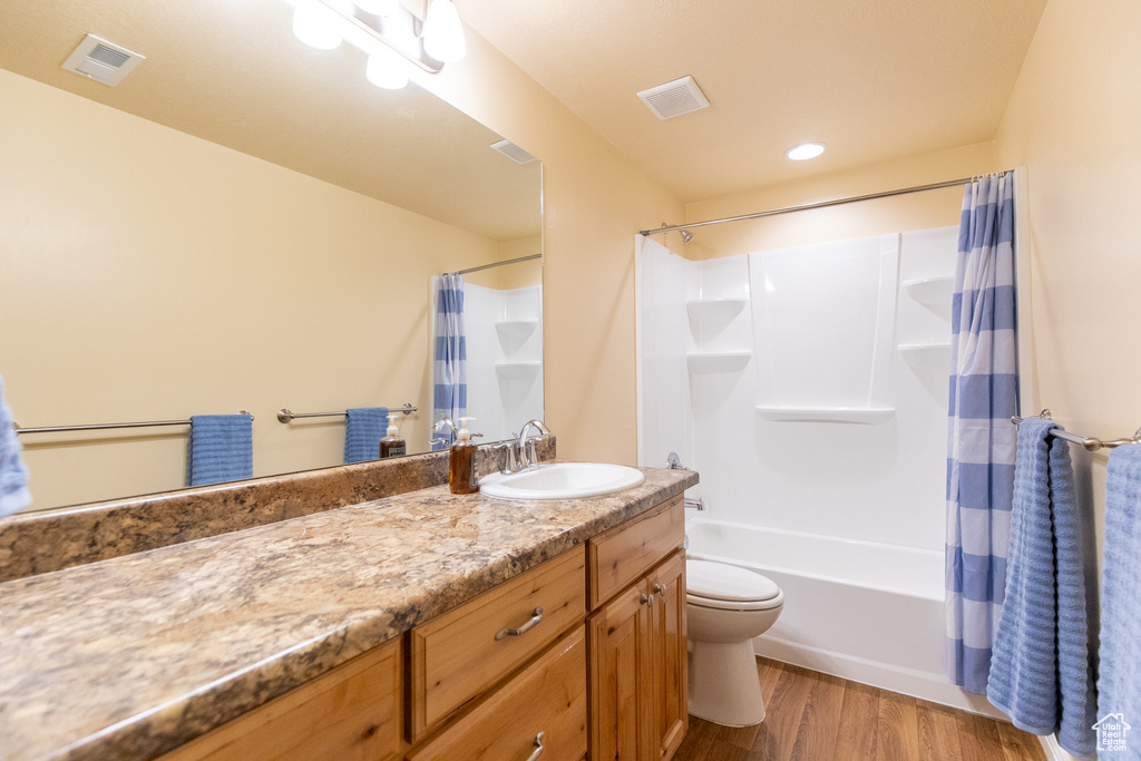 Full bathroom with shower / bath combo, toilet, vanity with extensive cabinet space, and hardwood / wood-style floors