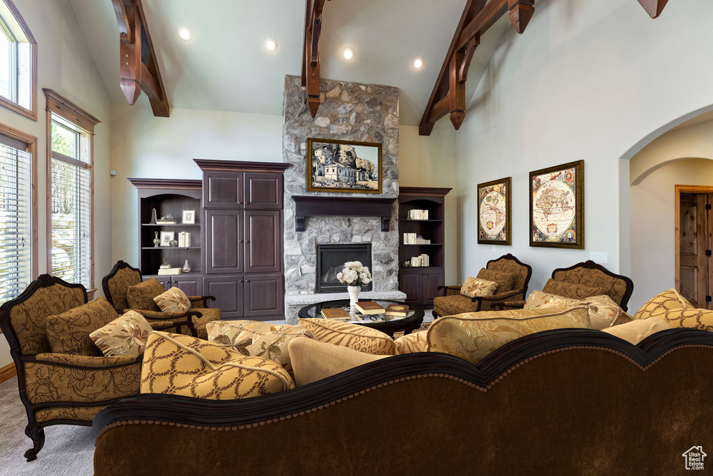 Carpeted living room with high vaulted ceiling, a fireplace, beam ceiling, and built in features