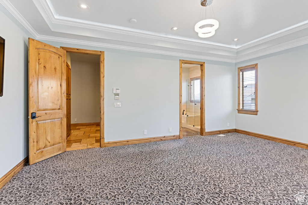 Unfurnished bedroom featuring ornamental molding, a tray ceiling, and carpet flooring