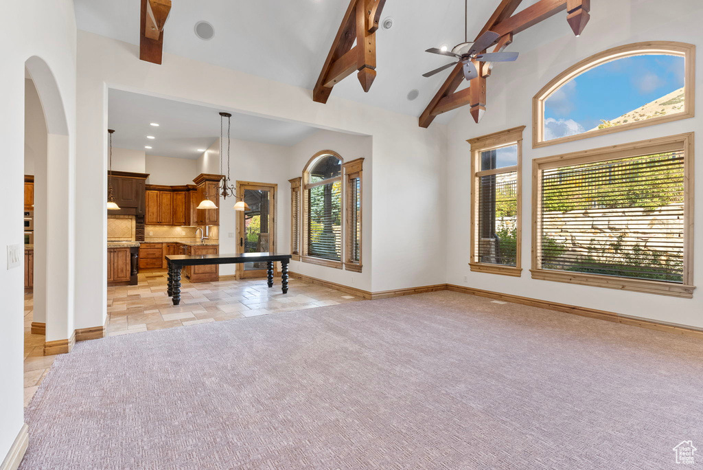 Rec room with a wealth of natural light, light colored carpet, beam ceiling, and high vaulted ceiling