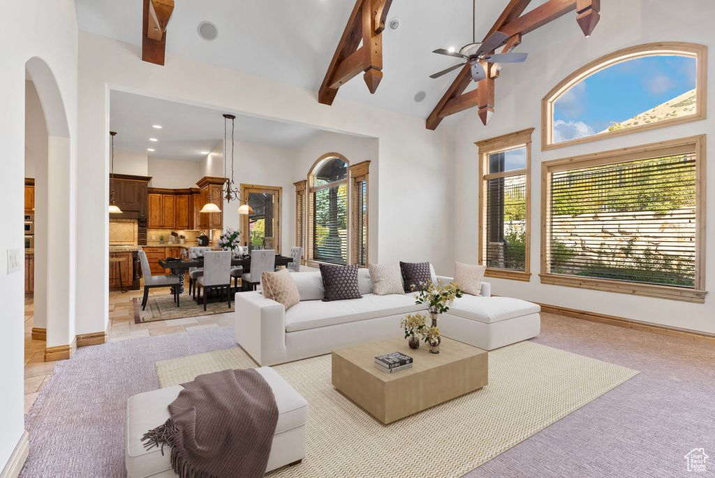 Living room featuring ceiling fan, a wealth of natural light, beamed ceiling, and high vaulted ceiling