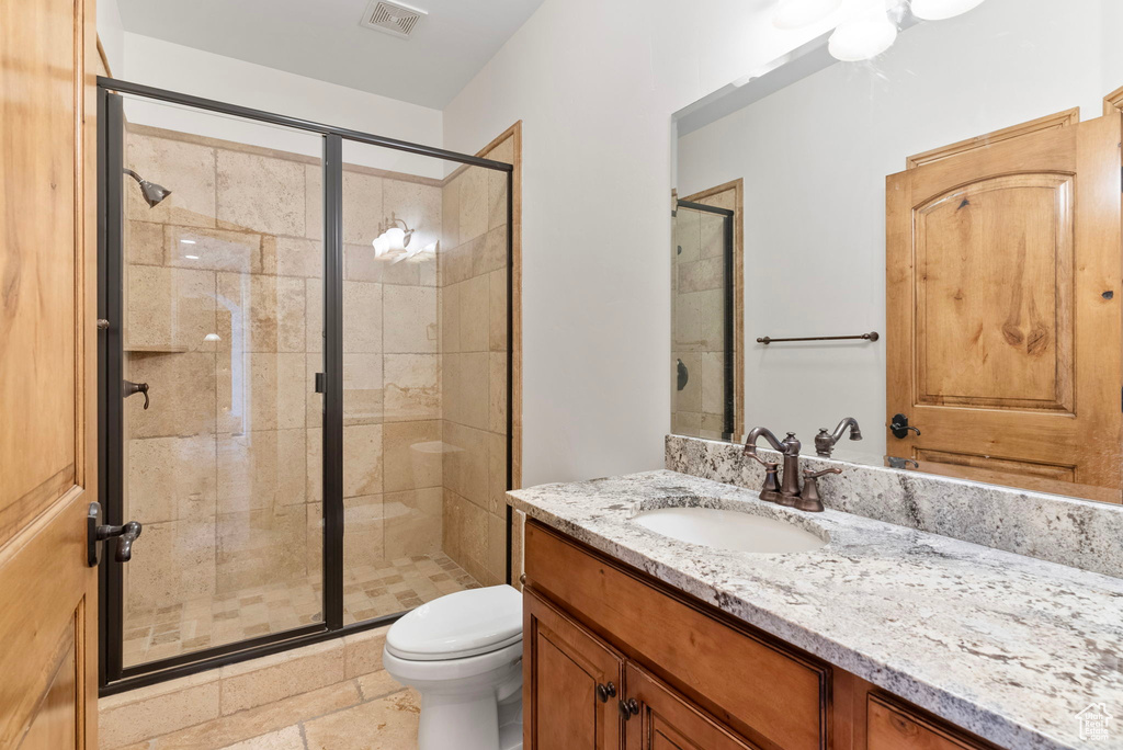 Bathroom featuring vanity, toilet, and a shower with door