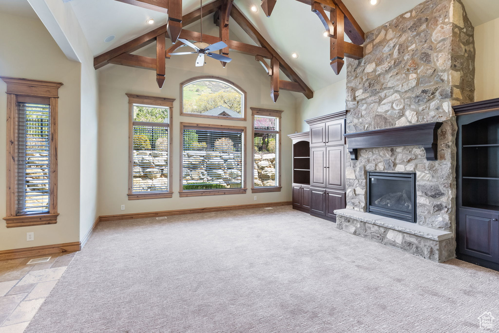 Unfurnished living room with high vaulted ceiling, a fireplace, carpet flooring, beam ceiling, and ceiling fan