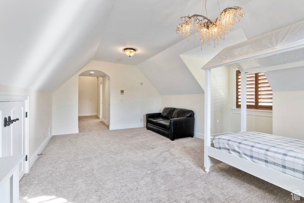 Carpeted bedroom with vaulted ceiling and a notable chandelier