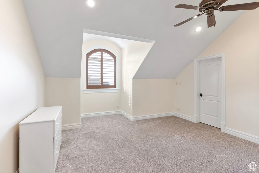 Additional living space featuring ceiling fan, light carpet, and vaulted ceiling