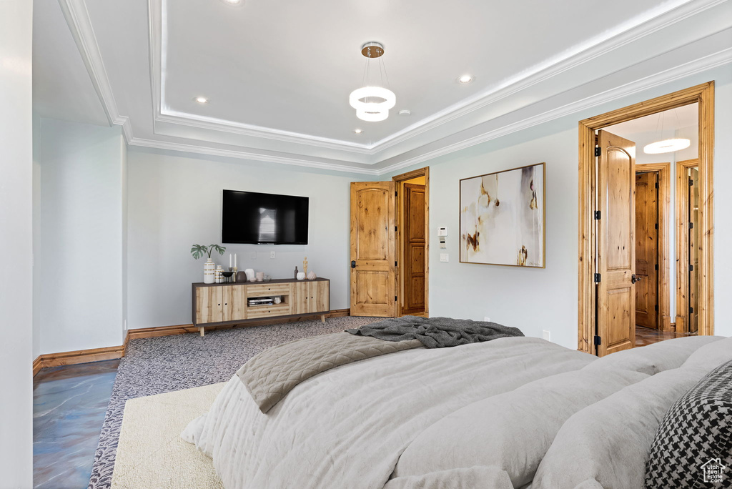 Bedroom with a raised ceiling, crown molding, and carpet