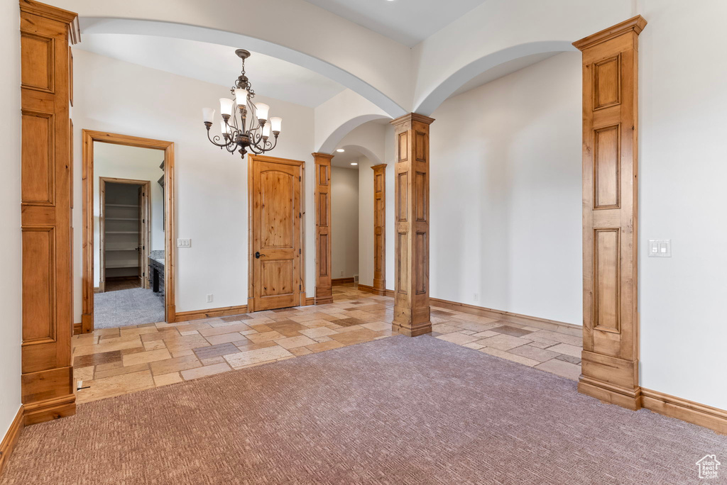 Unfurnished room with decorative columns and an inviting chandelier