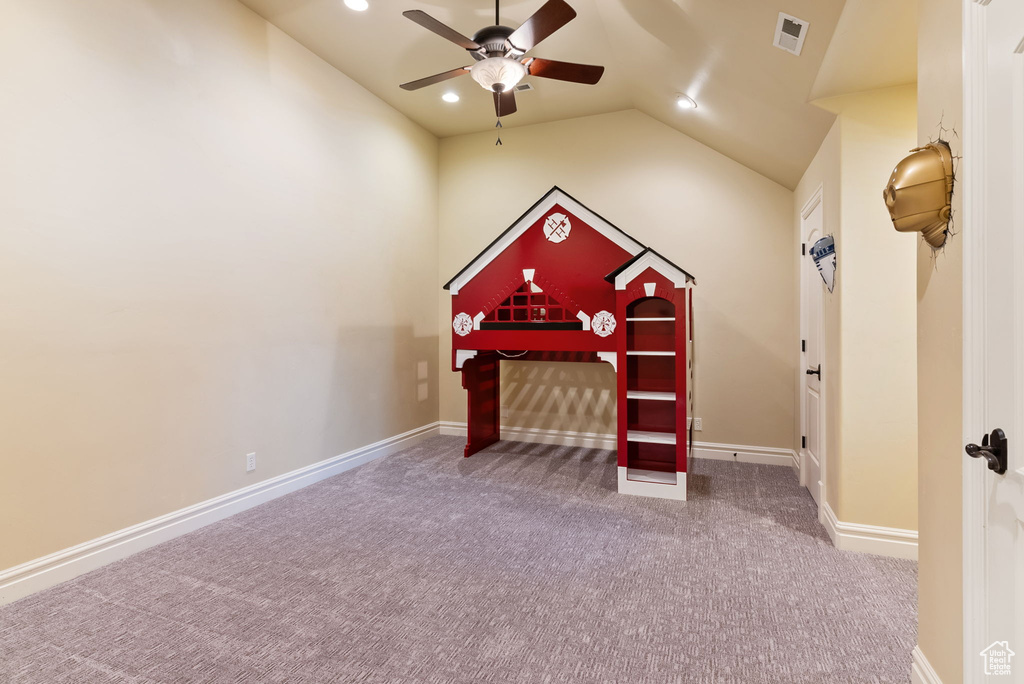 Interior space featuring vaulted ceiling, dark carpet, and ceiling fan