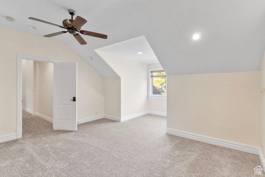 Bonus room with light carpet, ceiling fan, and vaulted ceiling