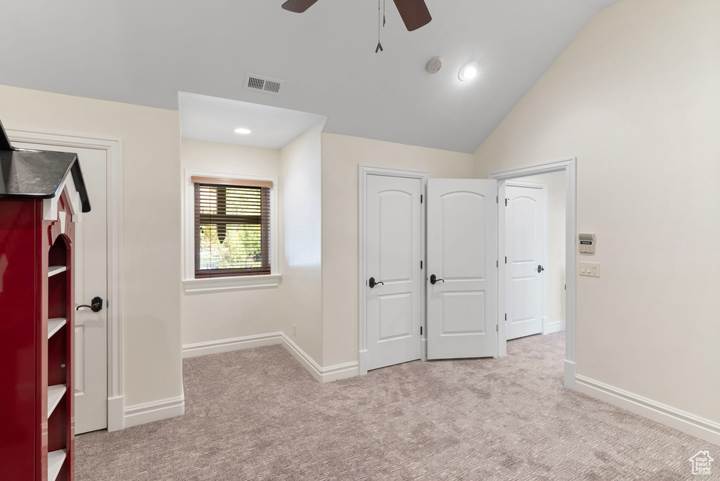 Unfurnished bedroom with lofted ceiling, light colored carpet, and ceiling fan