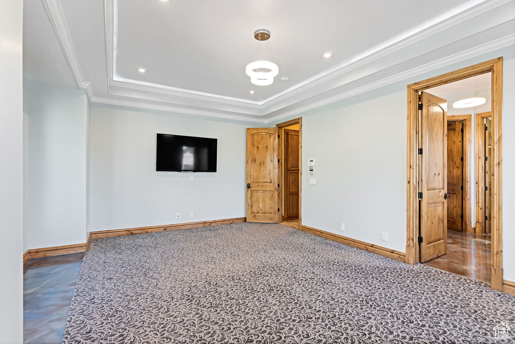 Carpeted spare room featuring a raised ceiling and crown molding