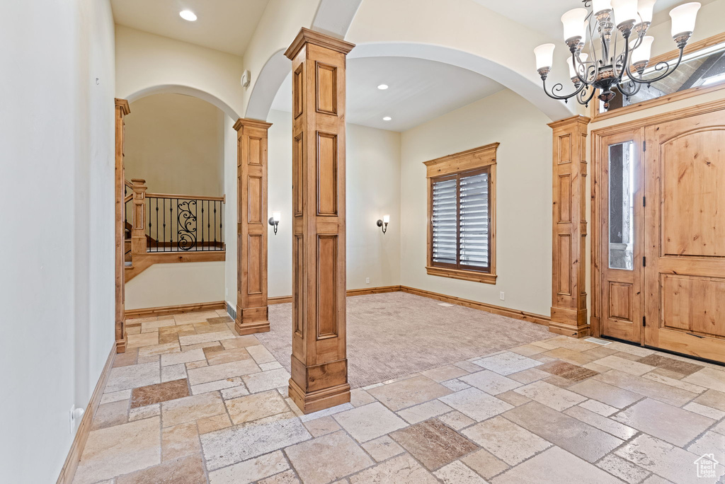 Entrance foyer featuring a chandelier, decorative columns, and light tile flooring