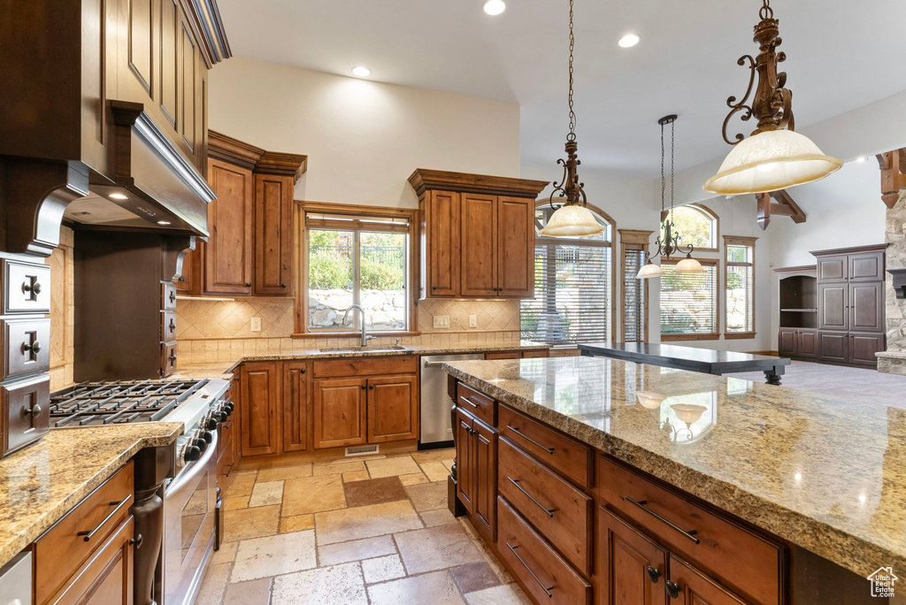 Kitchen featuring appliances with stainless steel finishes, hanging light fixtures, sink, and tasteful backsplash