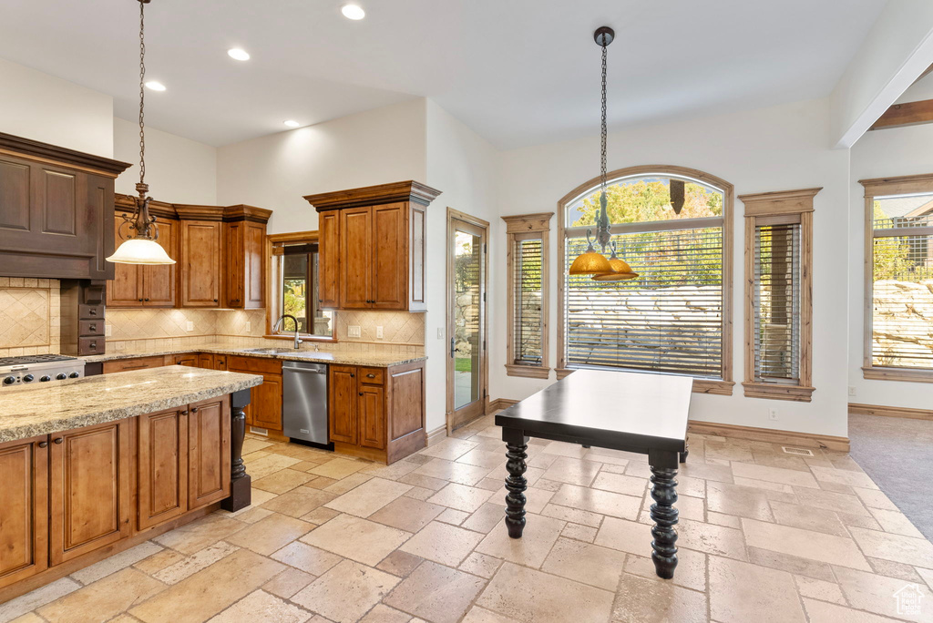 Kitchen featuring sink, light stone countertops, stainless steel dishwasher, hanging light fixtures, and decorative backsplash