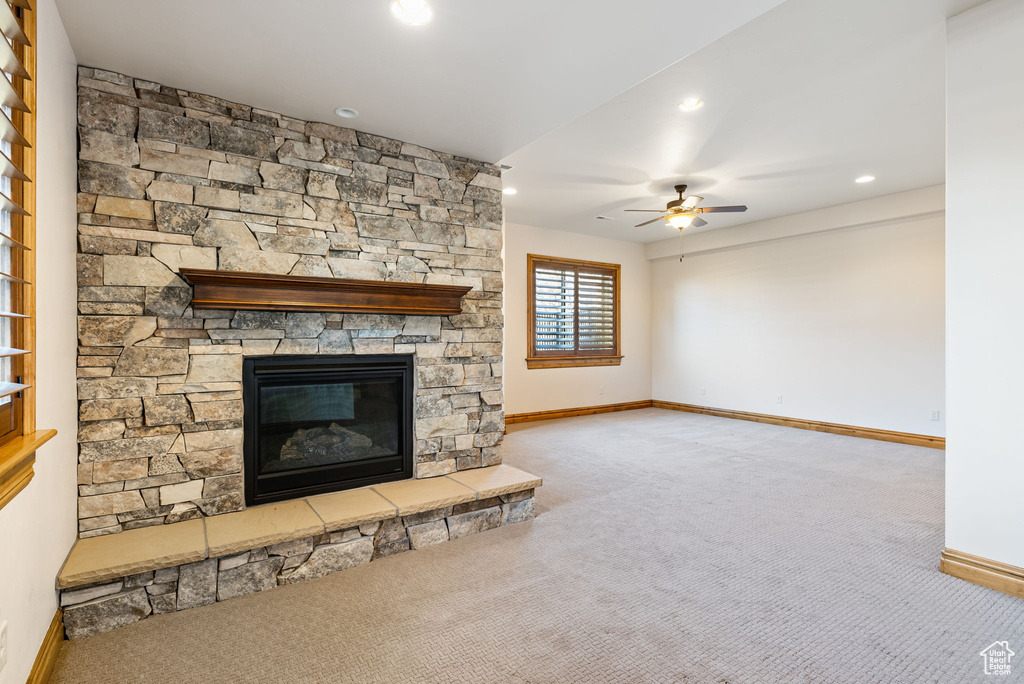 Unfurnished living room with a fireplace, light carpet, and ceiling fan