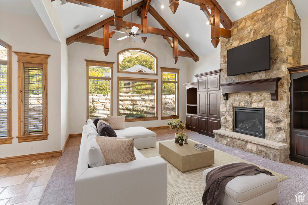 Living room with high vaulted ceiling, beam ceiling, ceiling fan, and a fireplace