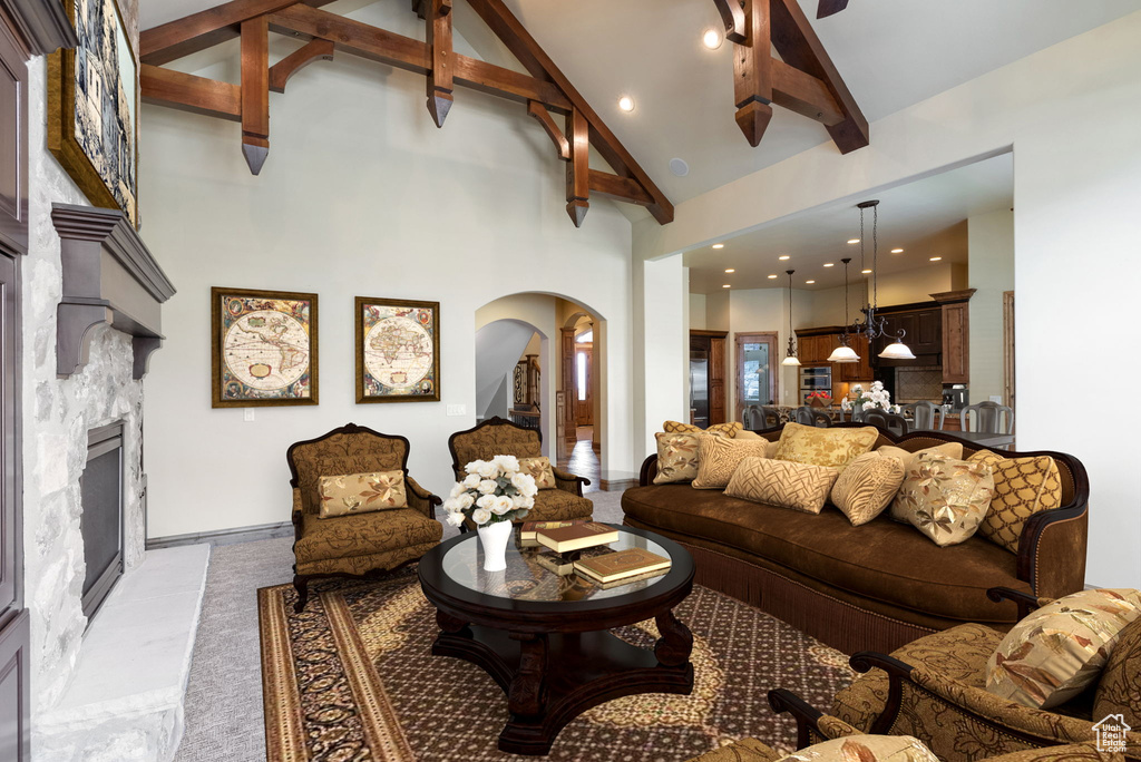 Living room with high vaulted ceiling, beamed ceiling, and a fireplace