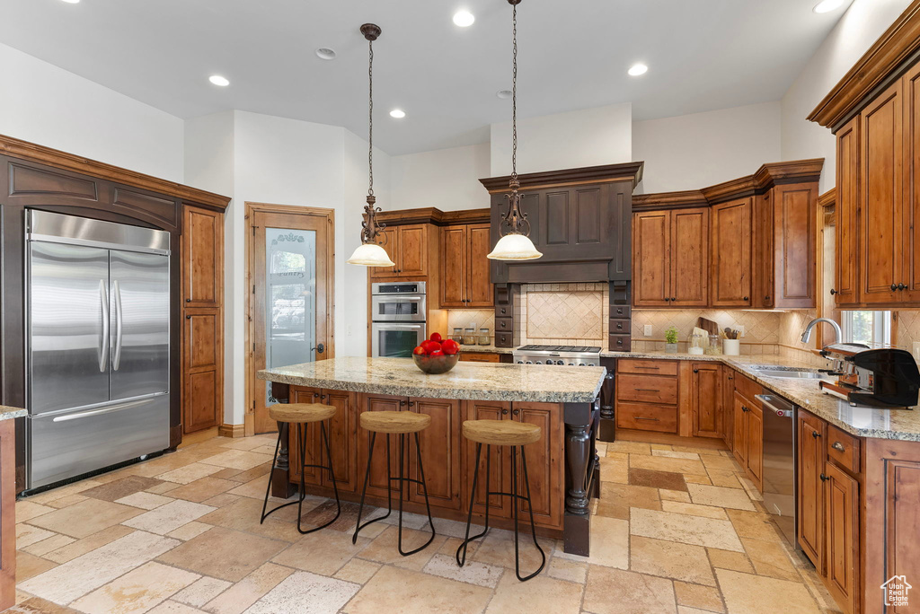 Kitchen with hanging light fixtures, high quality appliances, sink, and a center island