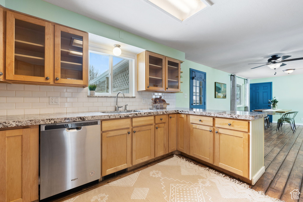 Kitchen featuring sink, tasteful backsplash, stainless steel dishwasher, light hardwood / wood-style flooring, and ceiling fan