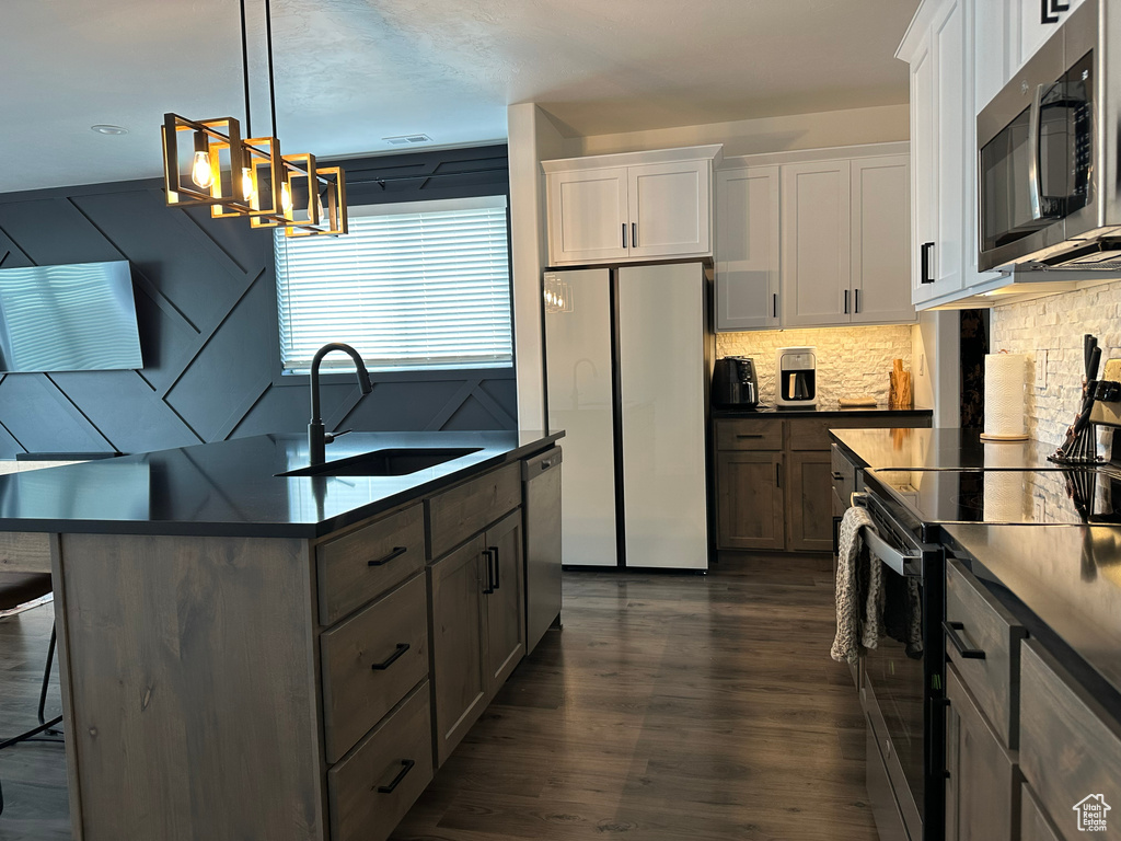 Kitchen featuring white cabinetry, appliances with stainless steel finishes, dark hardwood / wood-style floors, and backsplash