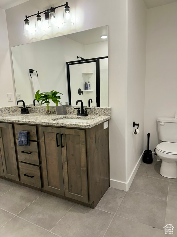 Bathroom featuring tile flooring, dual bowl vanity, and toilet