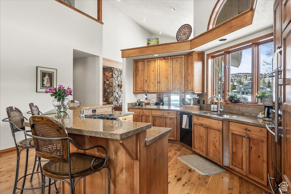 Kitchen featuring light hardwood / wood-style flooring, a breakfast bar, sink, and high vaulted ceiling