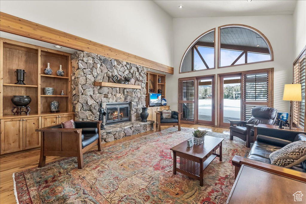Living room with a fireplace, hardwood / wood-style flooring, and high vaulted ceiling