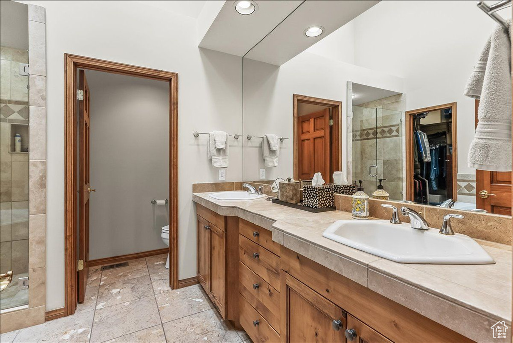 Bathroom with a shower with door, double sink, toilet, tile floors, and oversized vanity