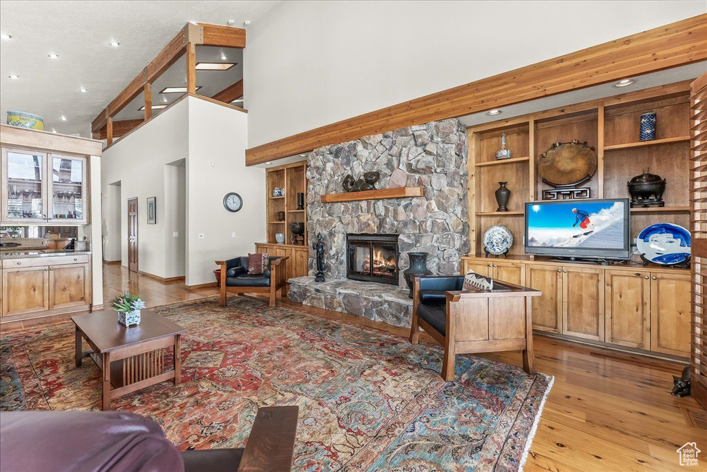 Living room featuring a stone fireplace, a high ceiling, light hardwood / wood-style floors, and built in shelves