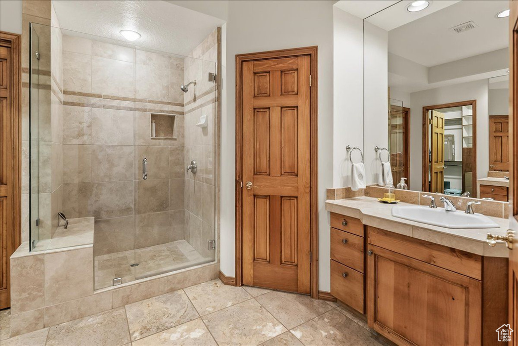 Bathroom featuring vanity, walk in shower, and tile floors