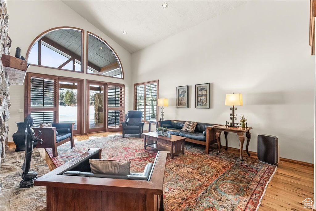 Living room with a wealth of natural light, high vaulted ceiling, and light hardwood / wood-style flooring