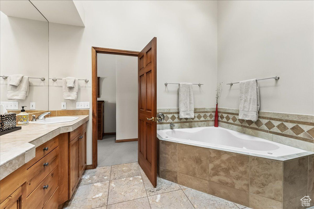 Bathroom featuring tile flooring, vanity, and a relaxing tiled bath