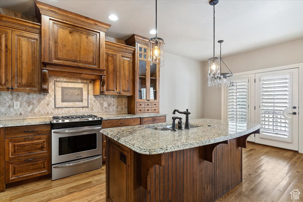 Kitchen featuring backsplash, a breakfast bar, stainless steel gas stove, and light stone countertops