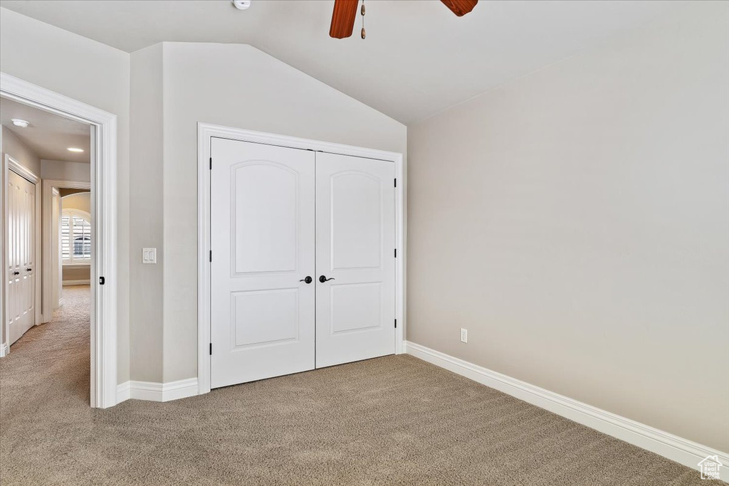 Unfurnished bedroom with lofted ceiling, light carpet, a closet, and ceiling fan